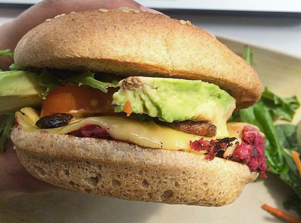 Karma Burger. A burger that is not only good for your health but good for the environment and animals :) It contains our signature lentil patty (made from sprouted lentils and beets), tempeh bacon, avocado, vegan cheese, lettuce, tomatoes, mamuket sauce on a sprouted grain sesame bun. It's served with a side of baked fries.