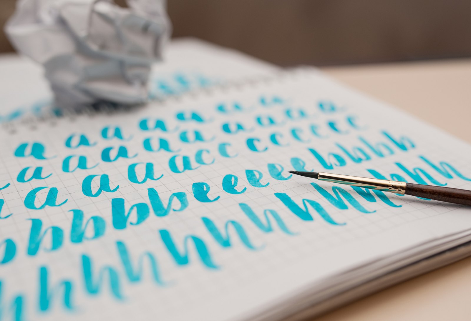 Teal watercolor brush lettering drills of the letters a, b and h in a sketchbook