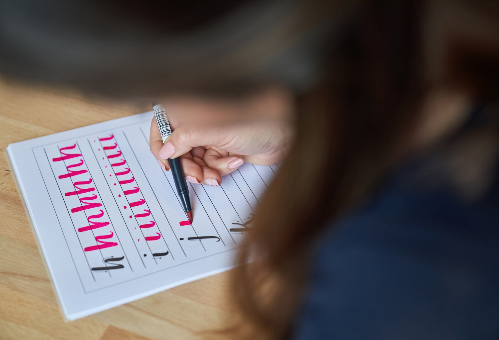Practicing pink brush pen strokes on a lettering worksheet