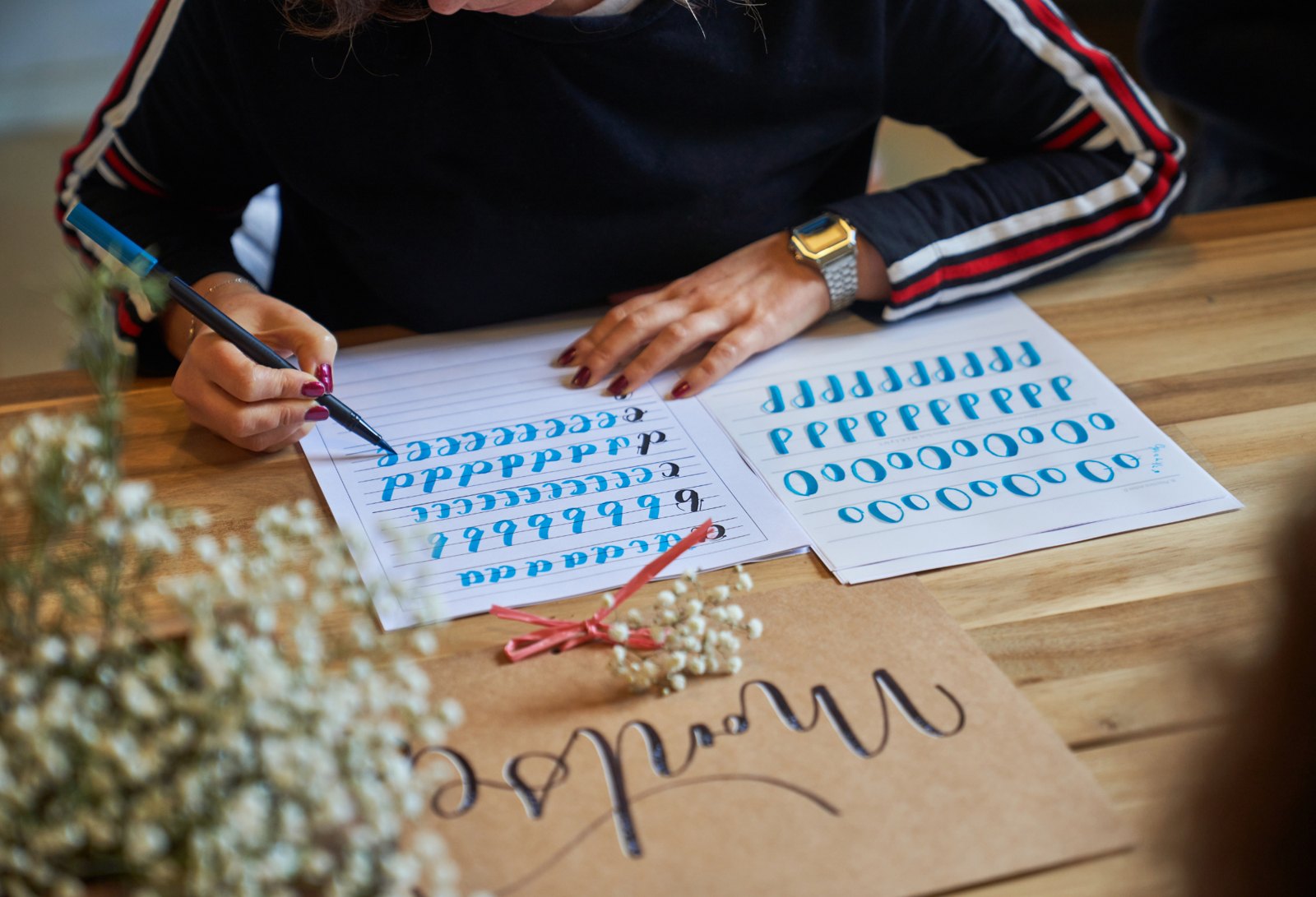 Watercolor lettering worksheets and a hand lettered thanks card on a wooden table